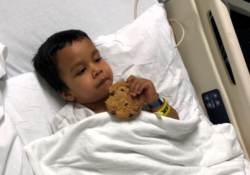 Yuvi in hospital bed with stuffed animal.
