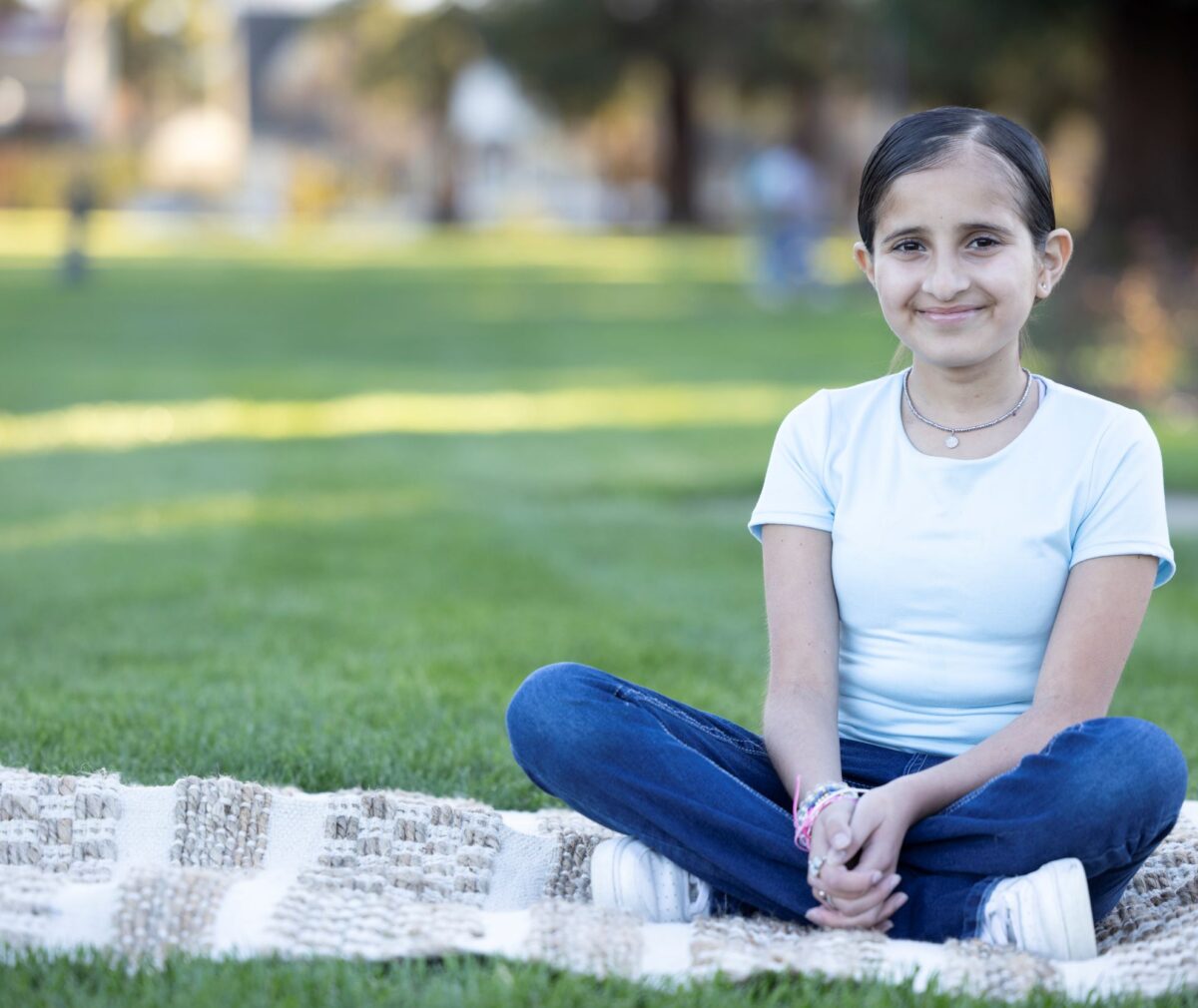 Zenaida sitting on blanket in park.