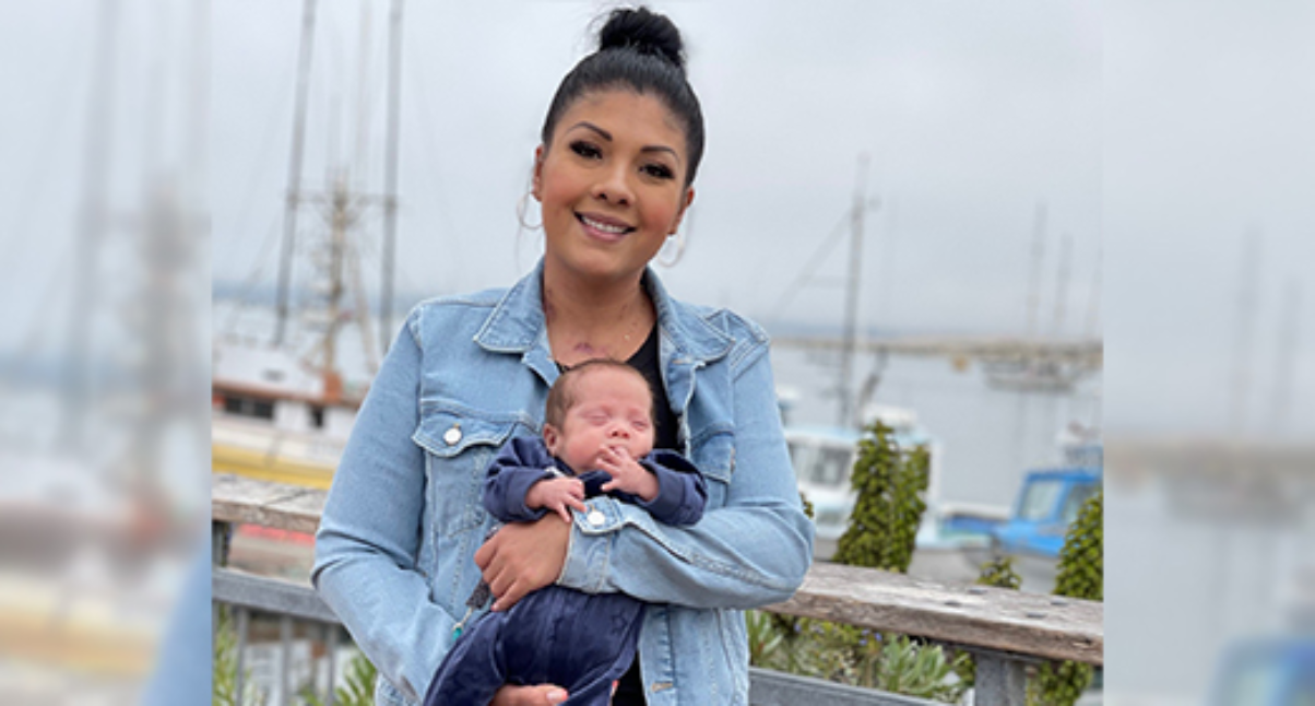 Woman standing by boats, smiling and holding child
