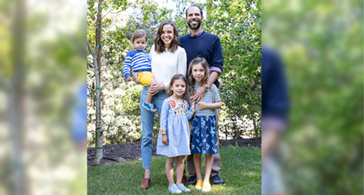 Family standing in front of trees, smiling