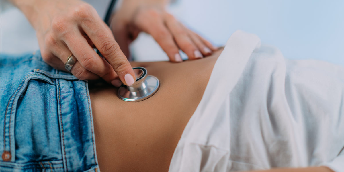 Stock photo of female physician's hands placing a stethoscope on a child's belly.