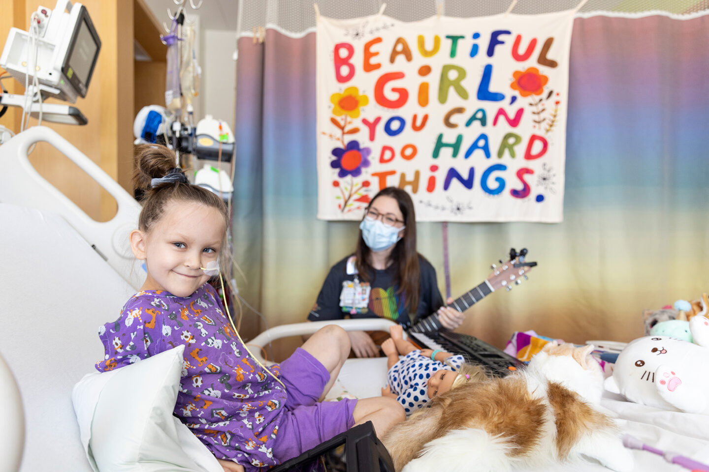 Ryan in hospital bed listening to music therapist play guitar.