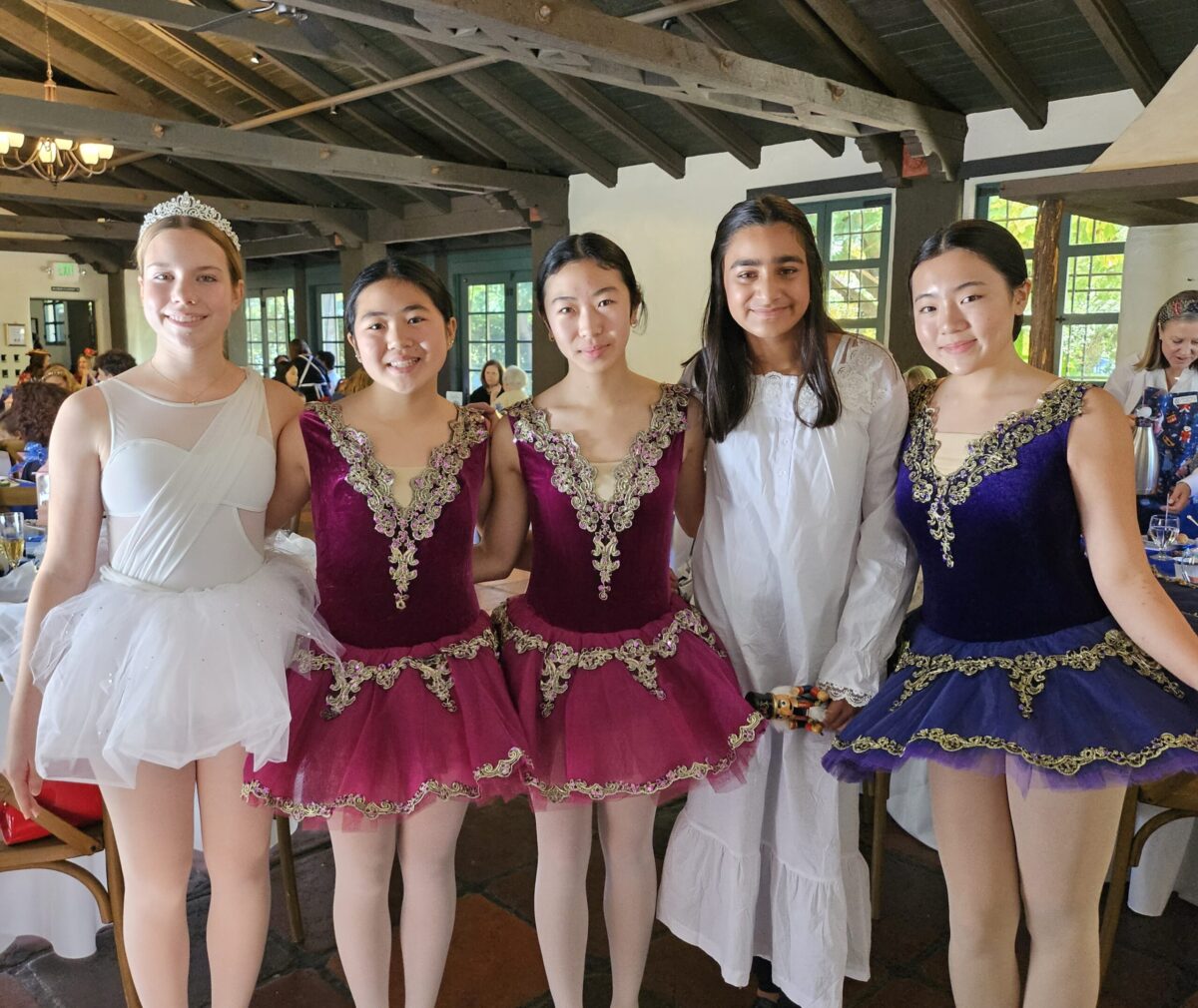 5 ballerinas pose together dressed in Nutcracker ballet costumes.