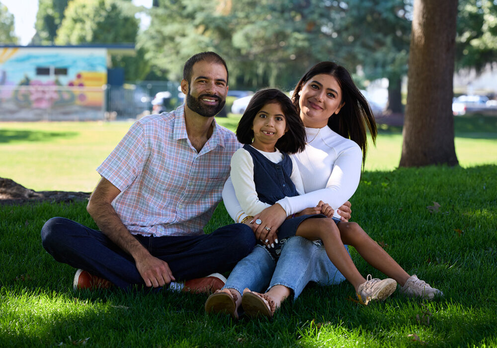Arya and family sitting down in park smiling at camera.