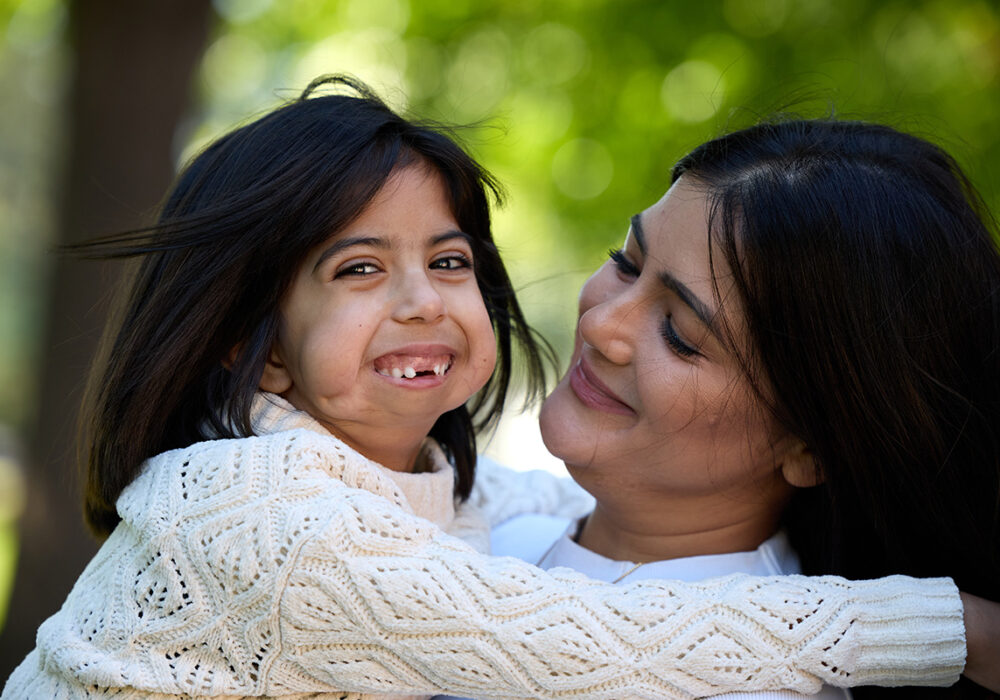 Arya and her mother hugging and smiling.