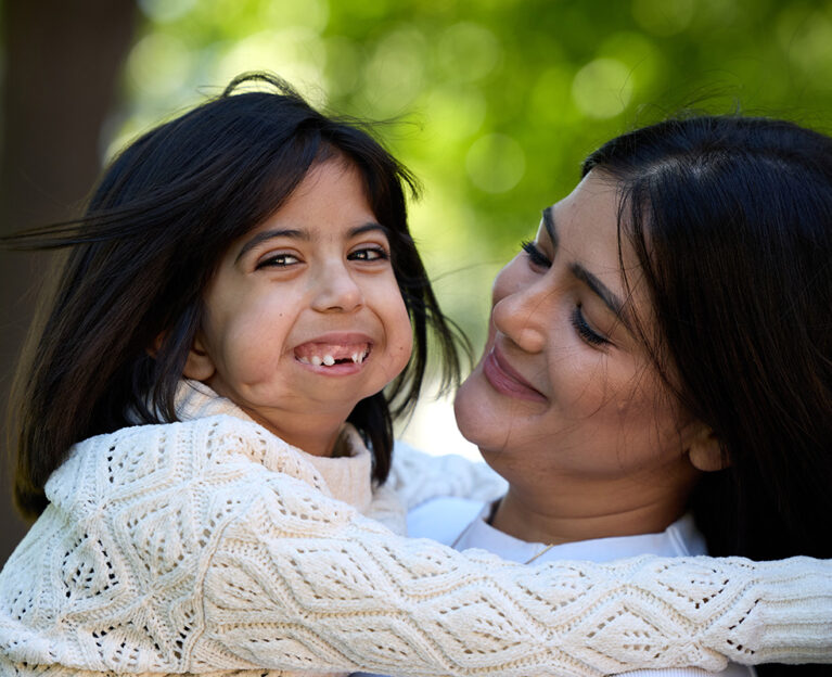 Arya and her mother hugging and smiling.