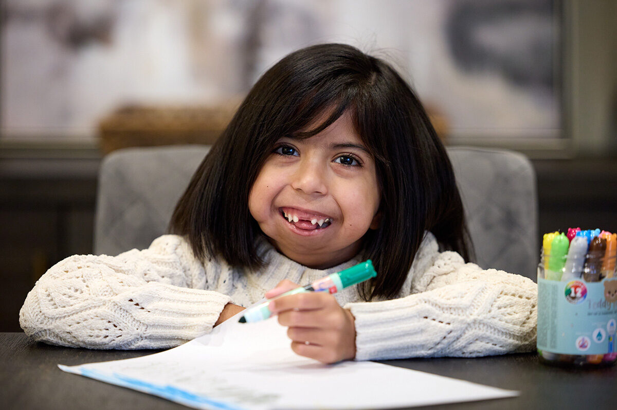 Arya coloring and smiling at camera.