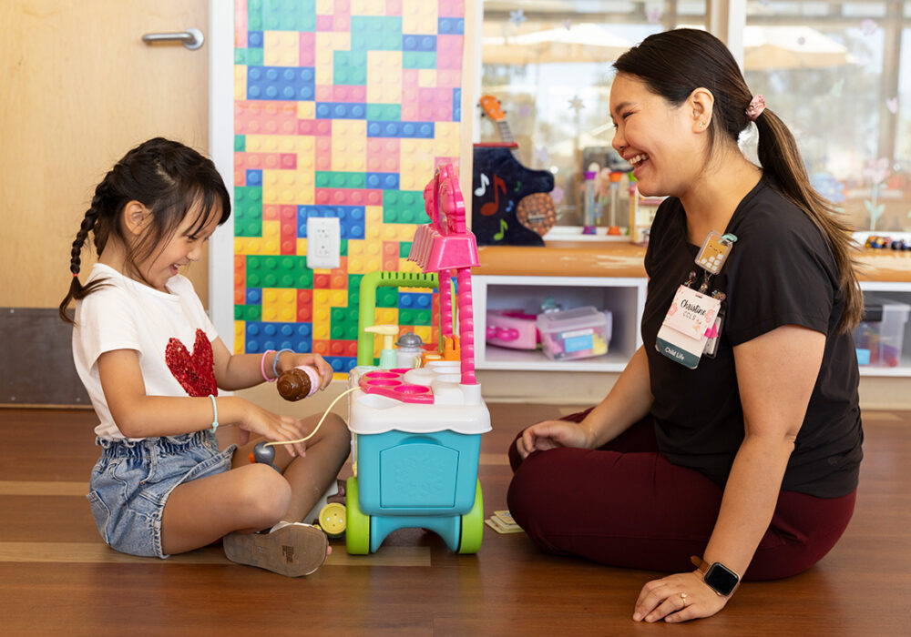 Cardiologist and Mikayla sitting facing each other playing with toys.