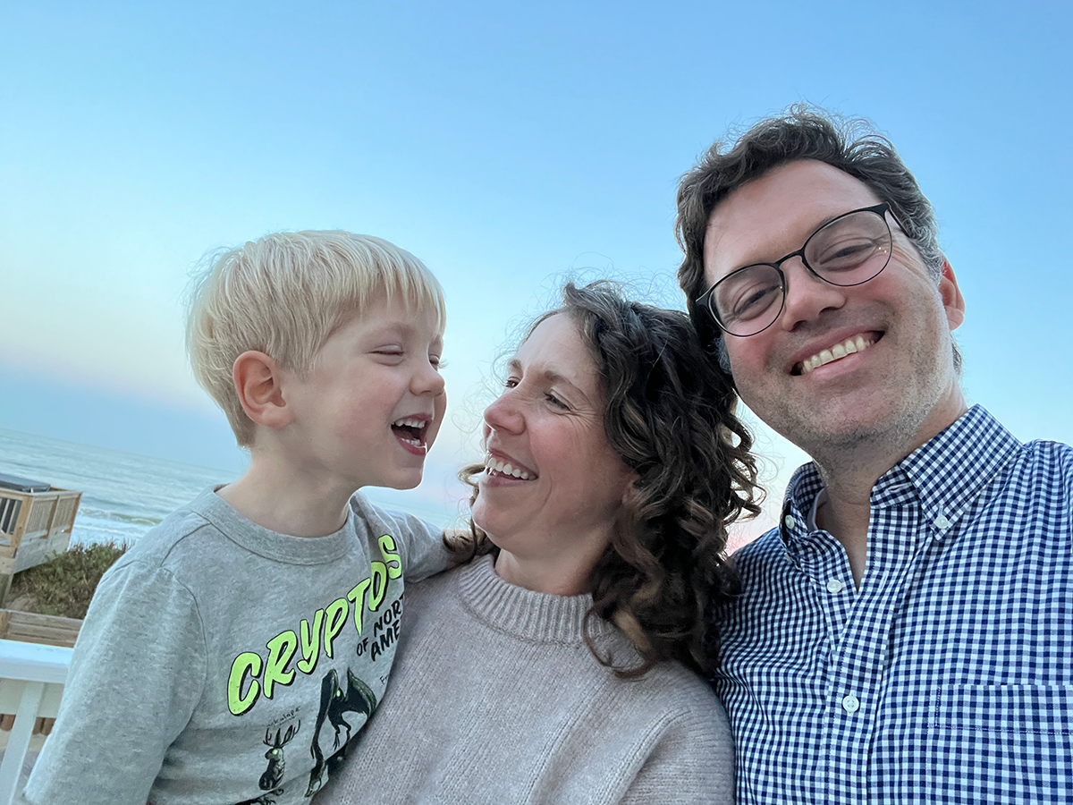 A family of three posing together and smiling.