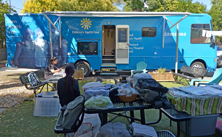 Nurses wait outside of the teen van which is parked at a school.