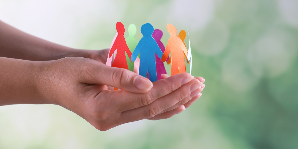 Stock photo of hands holding multicolored paper dolls that are connected and in a circle