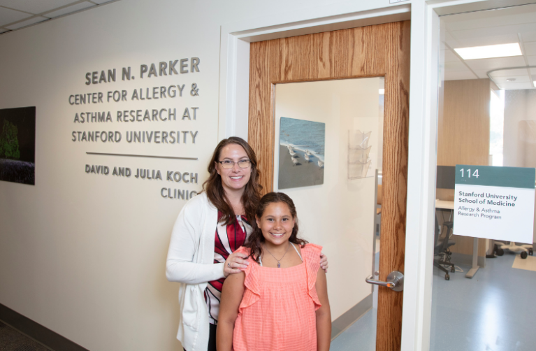 Entrance to the Sean N. Parker Allergy and Asthma Research Center with patient and doctor smiling in front of the door.