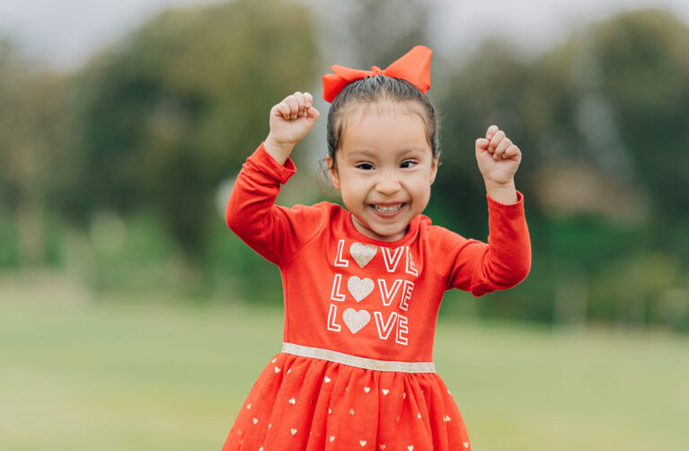 Former patient Iliana smiles in a red dress
