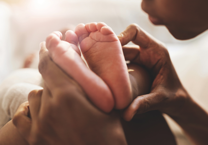 Adult holding newborn baby's feet.