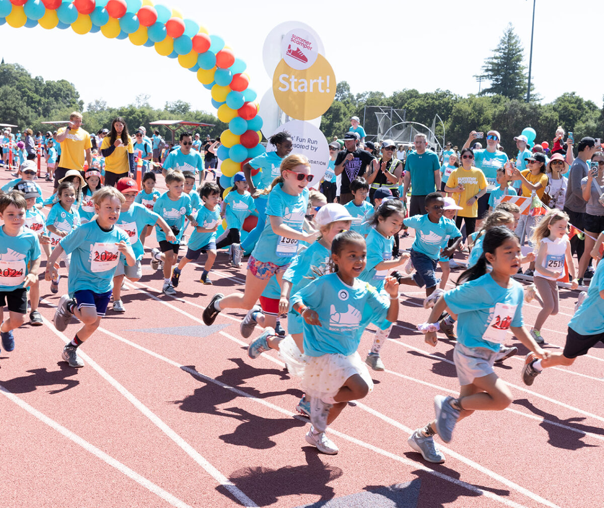 Kids are running on the Stanford track as part of Summer Scamper 2024.