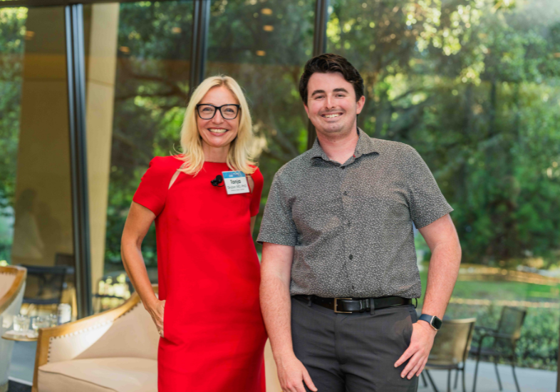 Two adults standing together posing for a picture and smiling.