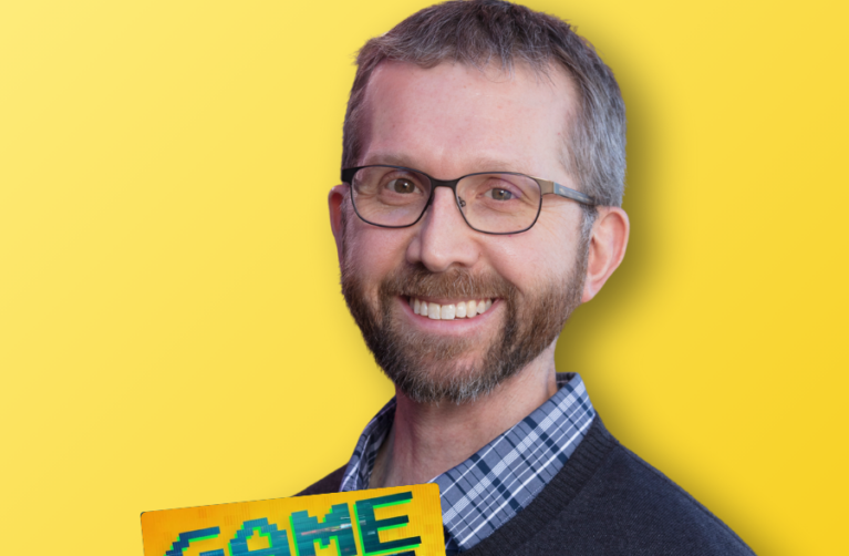 Adult pediatric cancer survivor smiling at the camera in front of a yellow backdrop. A logo of the Game Over Cancer podcast on the left-hand side.