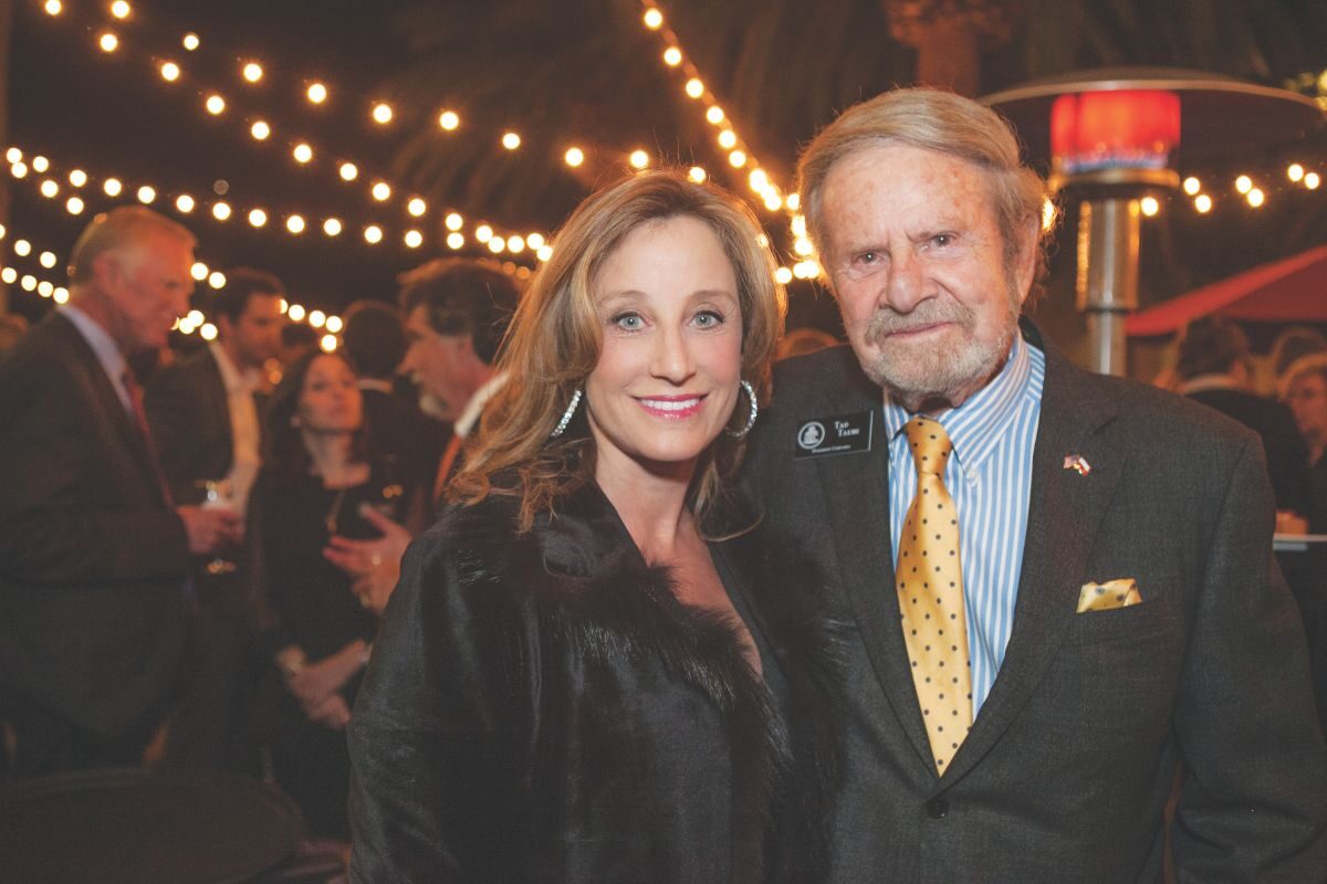 Two adults at a event posing and smiling at the camera.