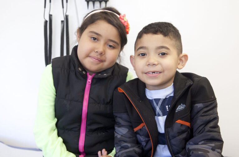 A brother and sister are seated next to one another.