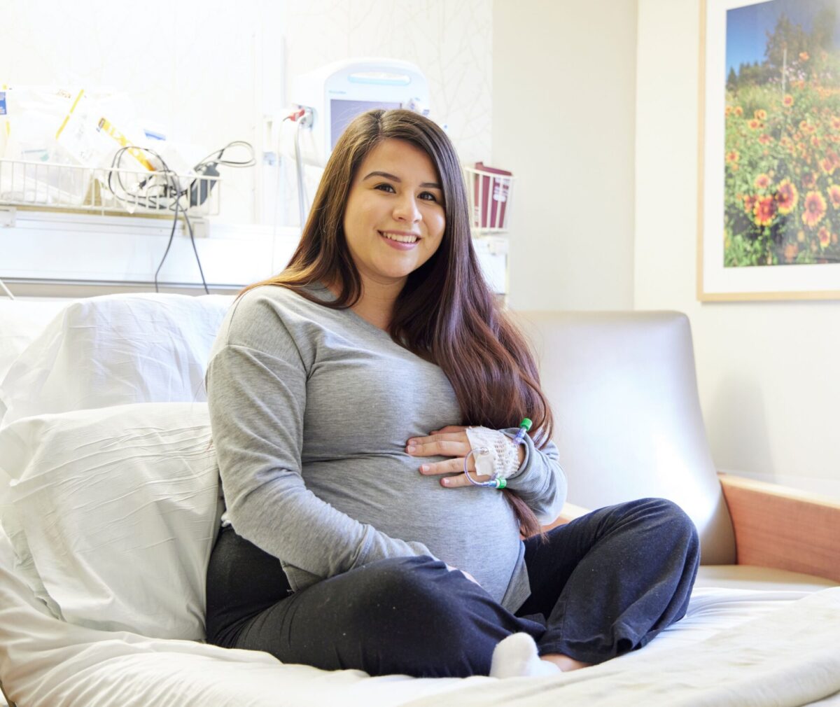 Pregnant woman seated on a hospital bed.