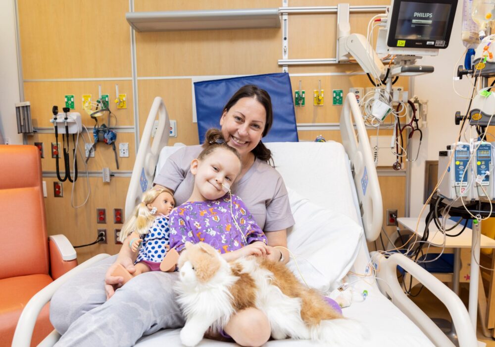 Ryan, age, 6, seated on a hospital bed with her mom.
