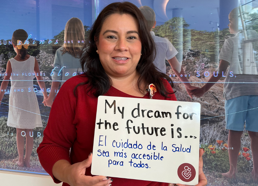 Hospital staff holding a white board that reads "My dream for the future is El cuidado de la salud sea mas accesible para todas."
