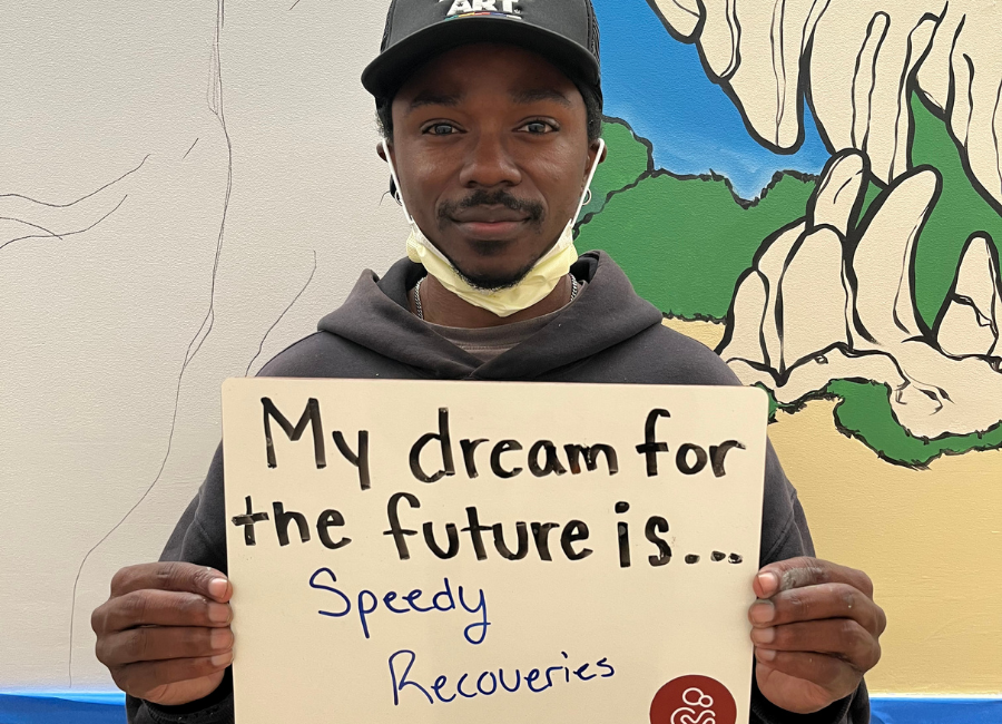 Hospital staff holding a white board that reads "My dream for the future is speedy recoveries."
