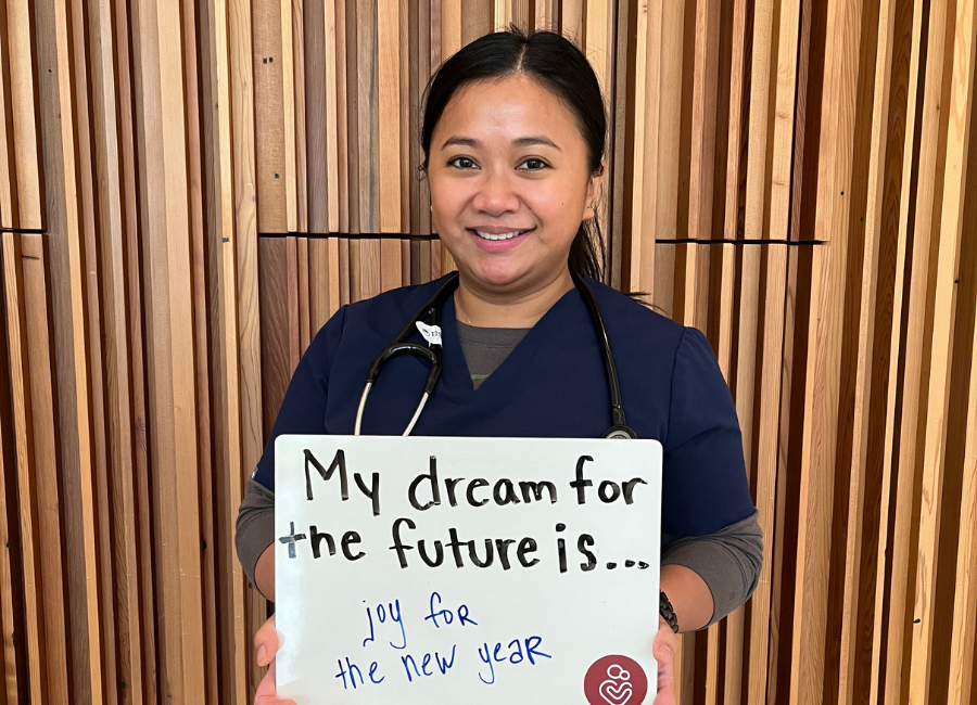Hospital staff holding a white board that reads "My dream for the future is joy for the new year."