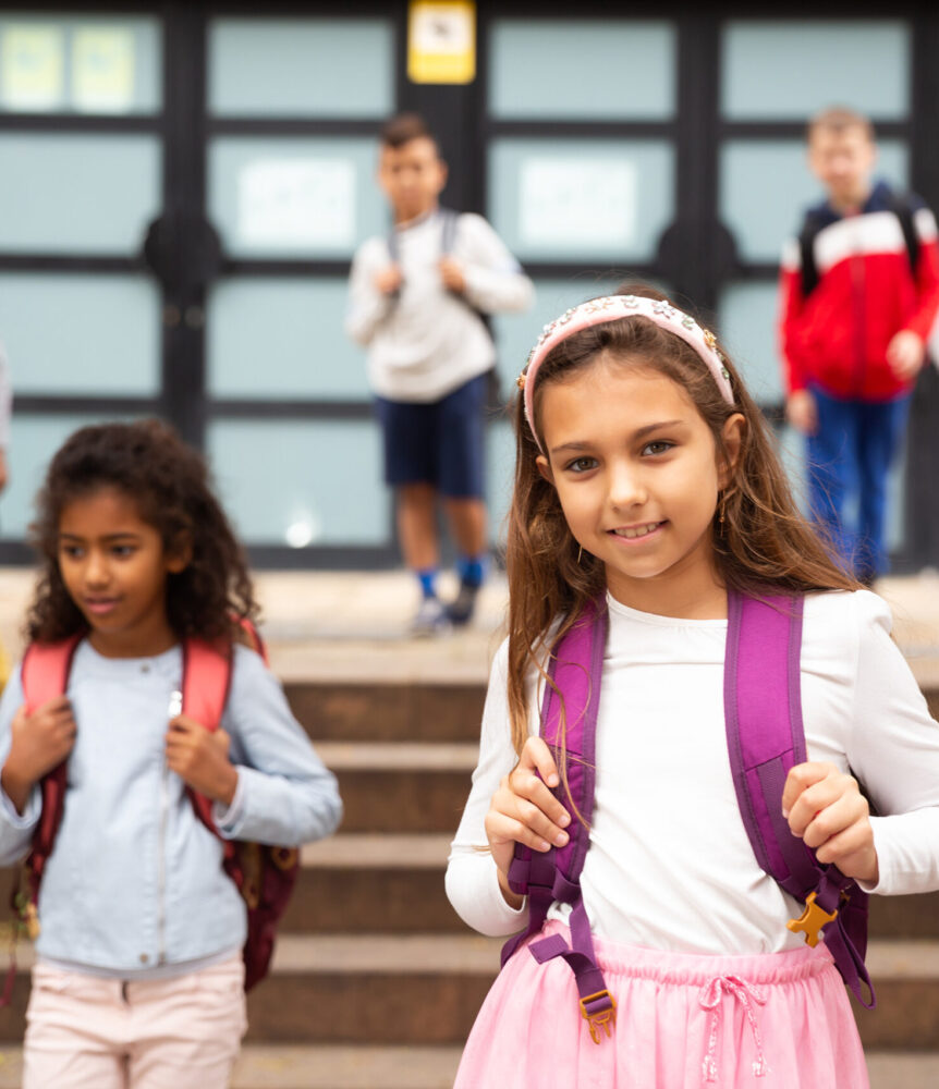 Portrait of smiling schoolgirl  standing on the street, kids on background