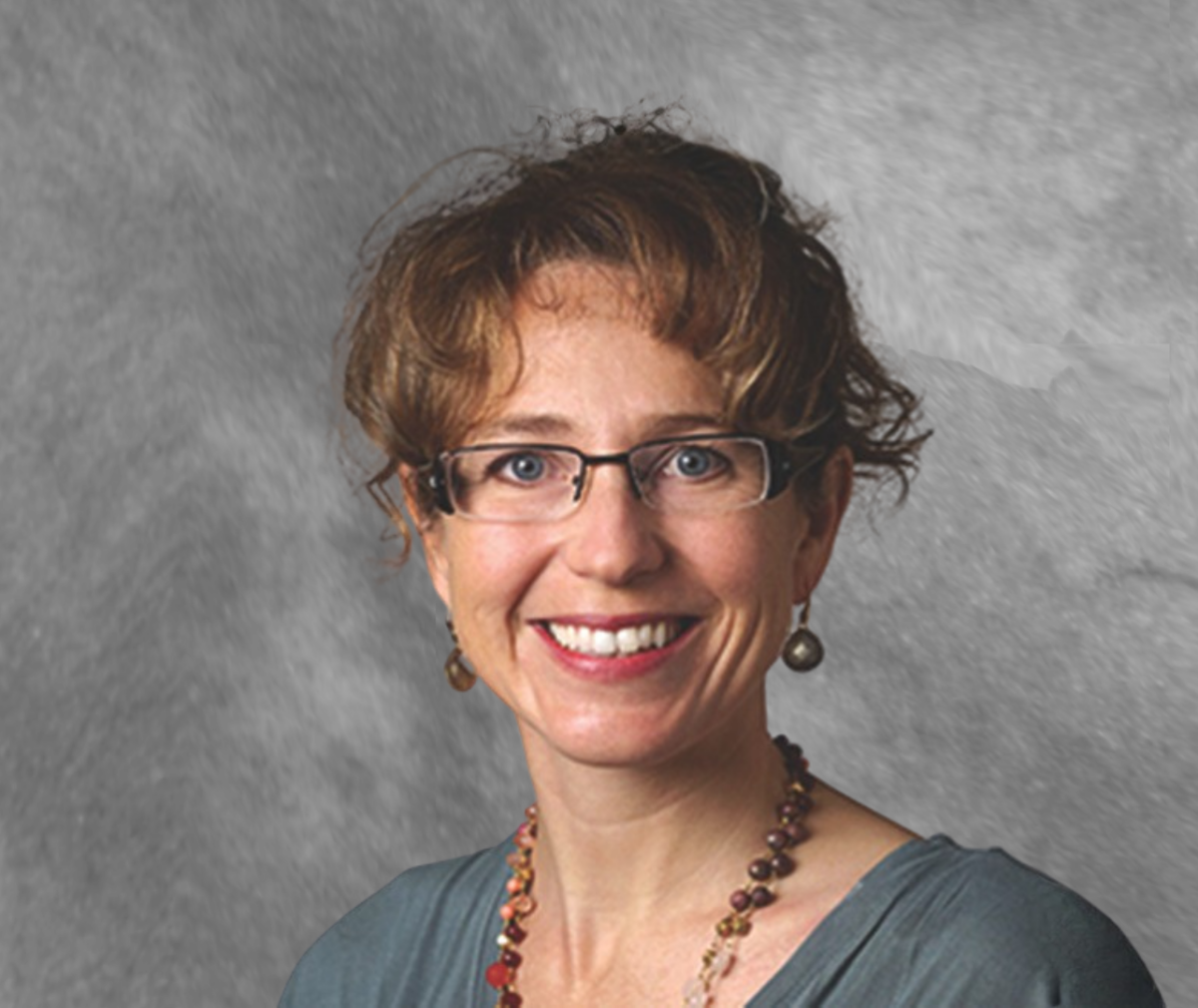 Stanford Medicine researcher Jennifer Frankovich, MD poses for a portrait photo and smiles at the camera in front of a grey backdrop.