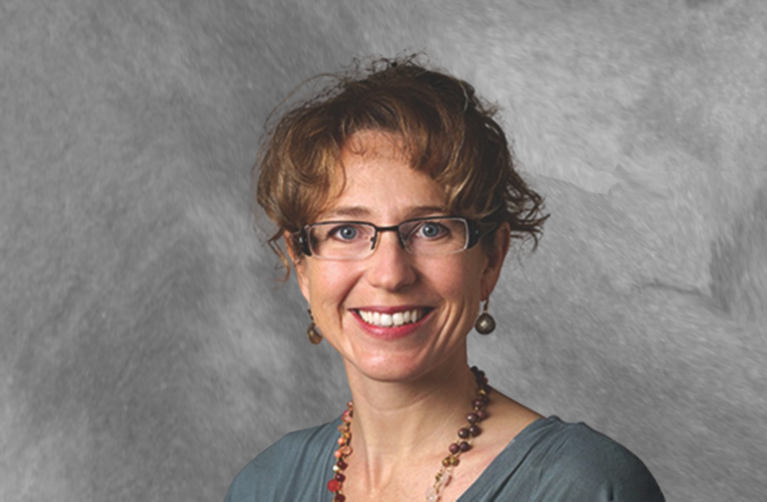 Stanford Medicine researcher Jennifer Frankovich, MD poses for a portrait photo and smiles at the camera in front of a grey backdrop.