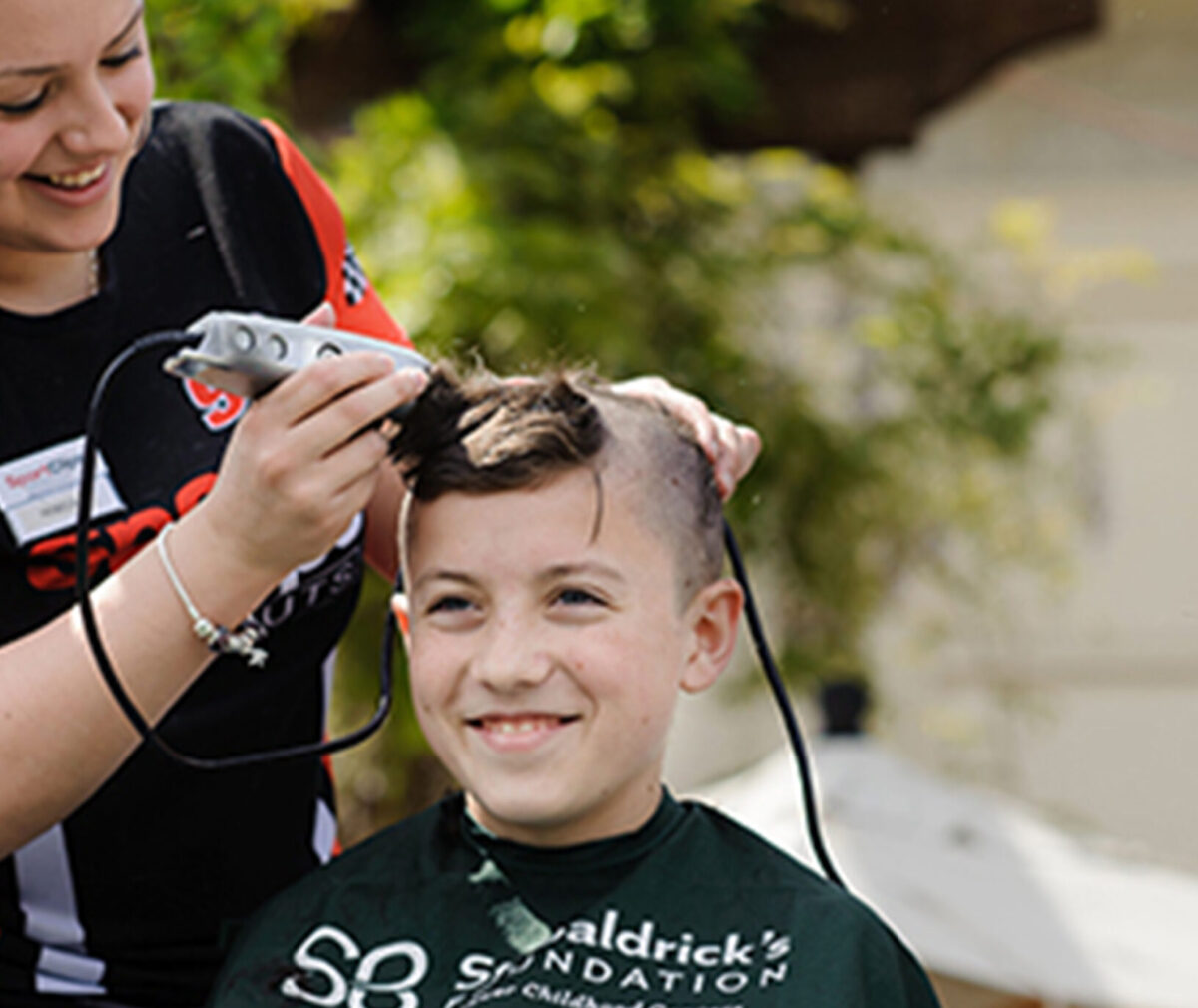 A boy is getting his head shaved.