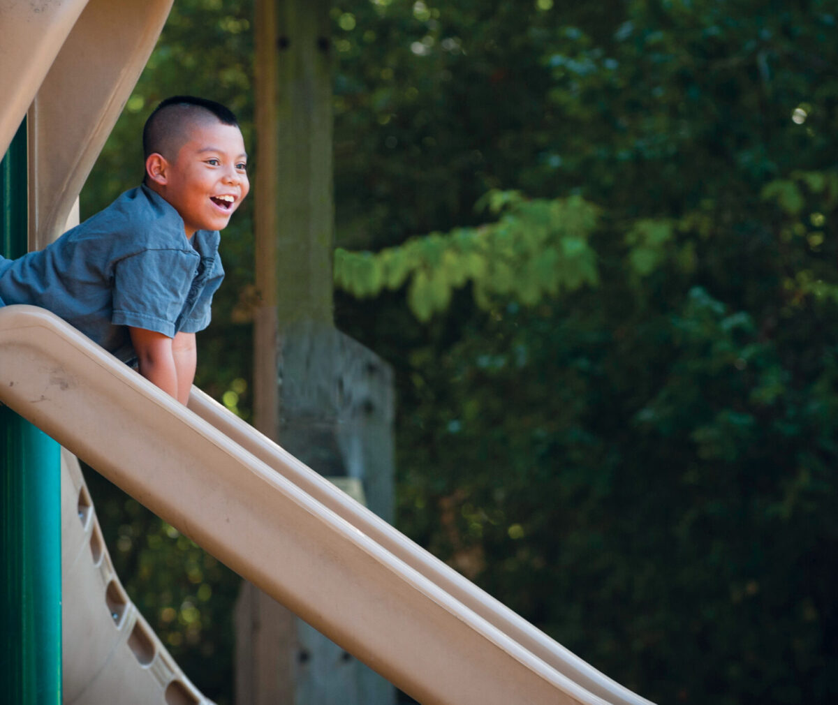 Leukemia patient Mateo Kohler smiles as he slides down a slide in a playground.