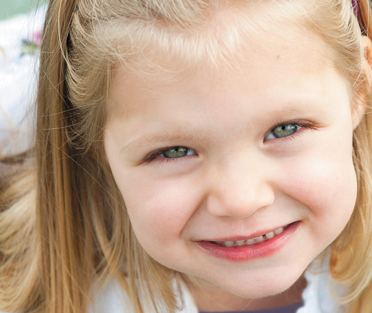 A young girl smiles into the camera.