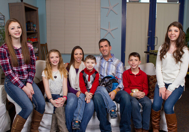 The Bingham family--three girls and two boys with their parents--is seated on a couch.