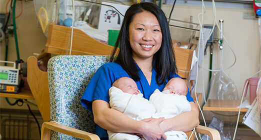 Adult holding two newborn babies.
