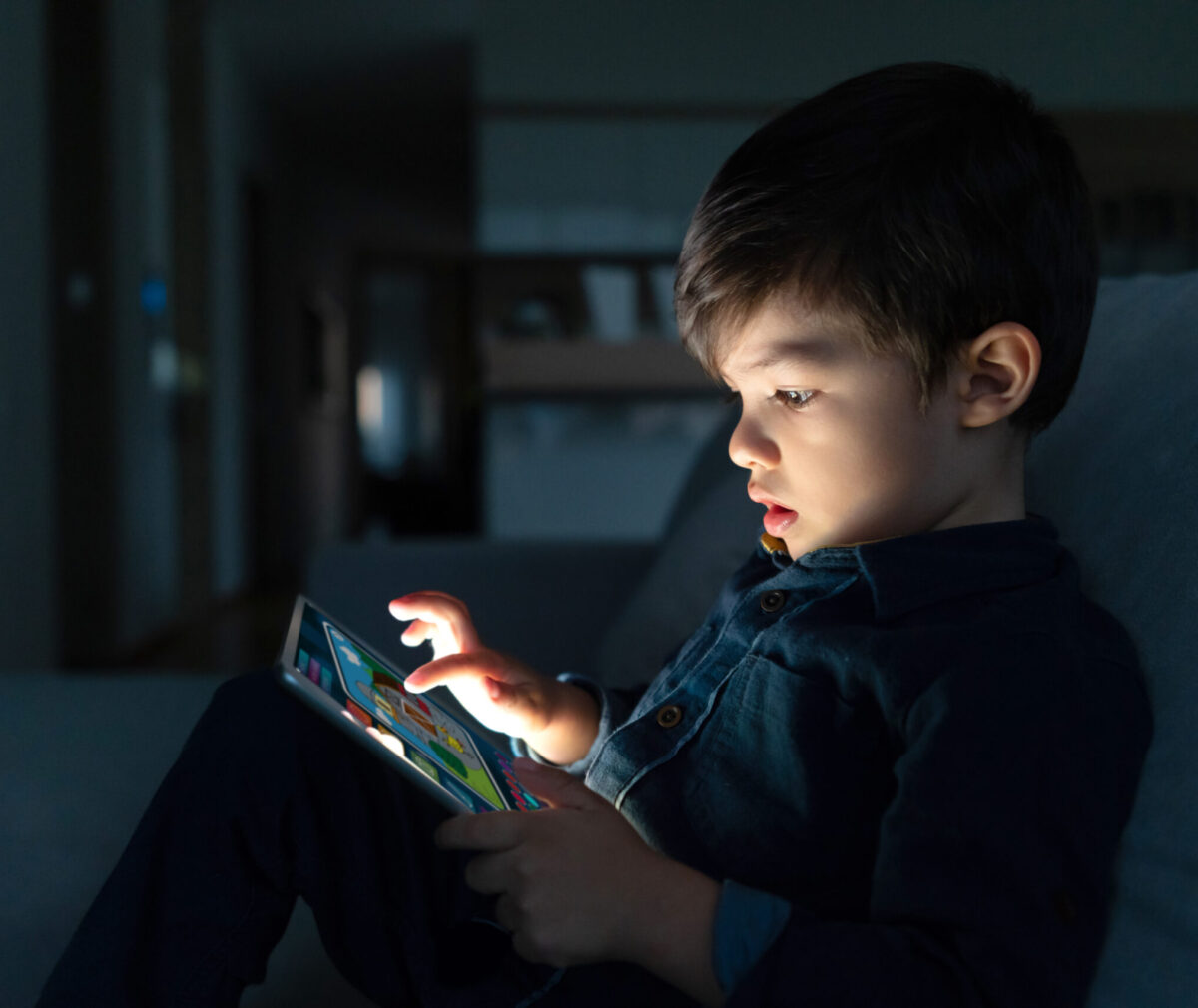 Young boy using a digital tablet at home at nighttime